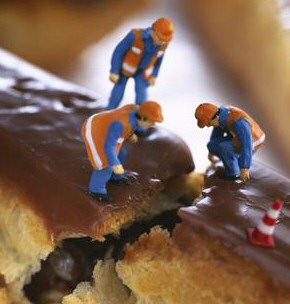 Little construction men sitting on an eclair which, to them, is life-sized