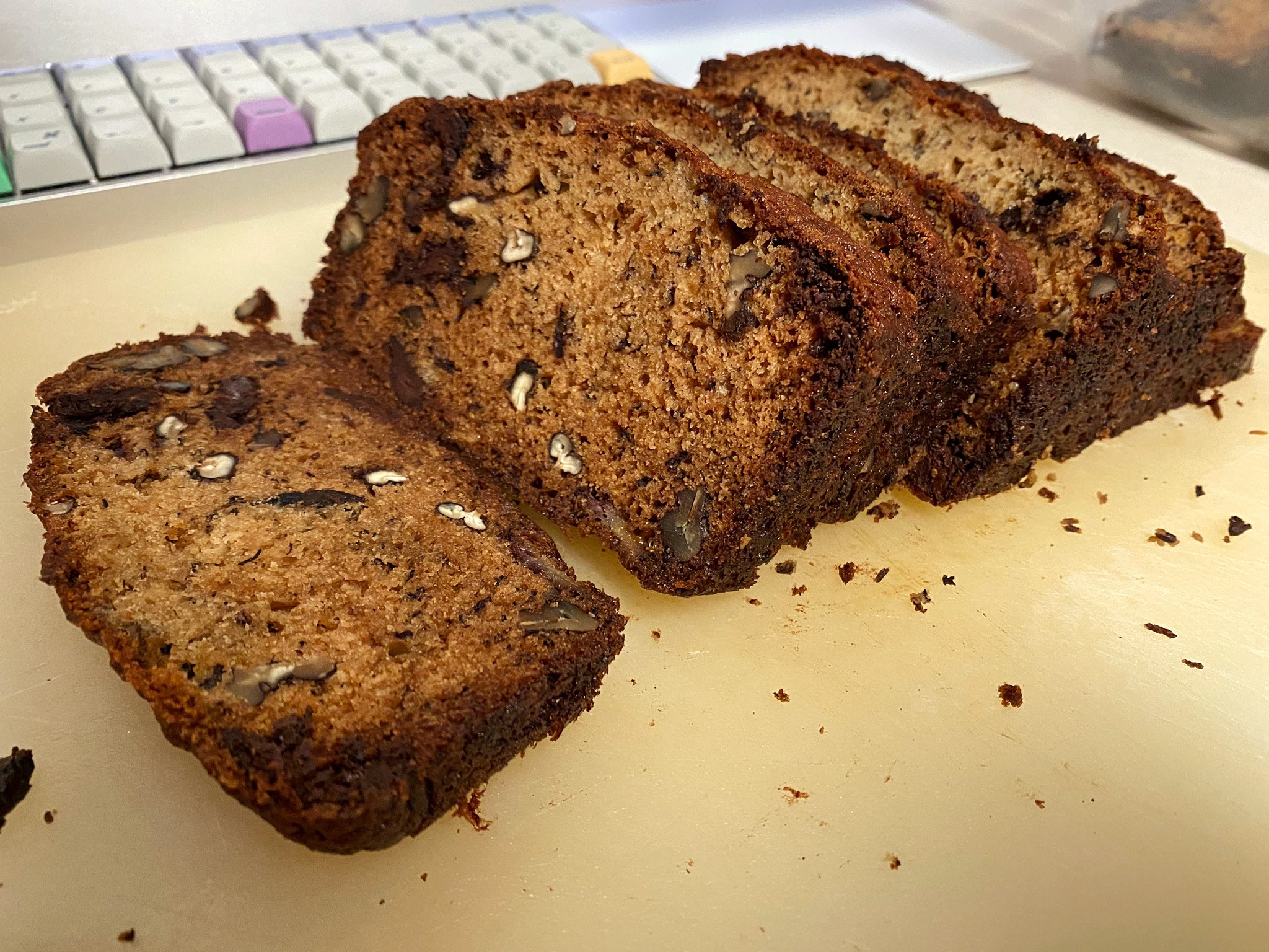 Sliced chocolate-chip banana-nut bread on a cutting board in Ashleyâ€™s kitchen. In the background is Ashleyâ€™s 21-inch kitchen iMac and her Preonic keyboard